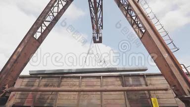 龙门吊从货车上卸下型材管道，在仓库装载金属，大型龙门吊